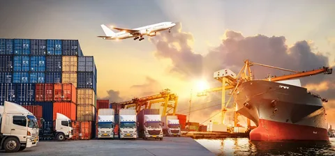 Busy shipping port with containers, trucks and cargo ship at sunset